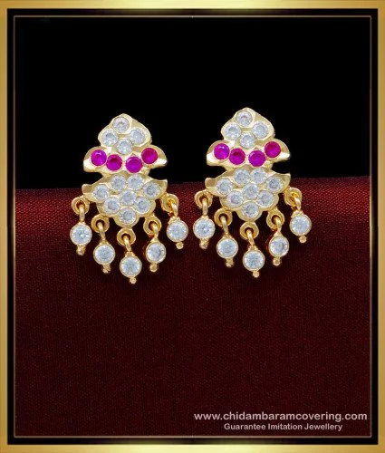 Premium Photo | A pair of gold earrings with red stones and a pink flower  on the side.